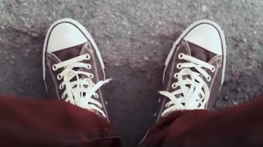 Bordo kot pantolon ve beyaz dantel ile siyah beyaz spor ayakkabı bir adam ayakları ile yere vuruyor. Bir adam bir müzik ritmini ayaklarıyla yener. Close.