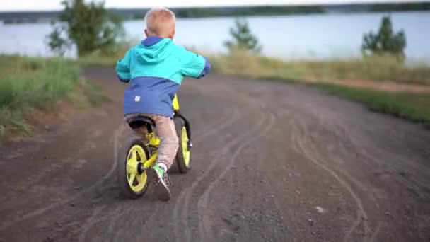 Bir Ceket Pantolon Küçük Çocuk Bir Runbike Üzerinde Yol Boyunca — Stok video