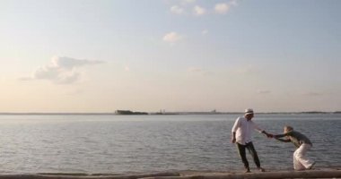 erkek ve kadın batan güneşin altında deniz boyunca koşmak