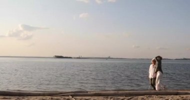erkek ve kadın batan güneşin altında deniz boyunca koşmak