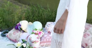 Beyaz elbiseli bir kız figürü ve elinde çiçekle nehrin yanındaki ormanda.