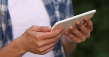 Tablet mavi tişörtlü bir adamın elinde, yakın plan.