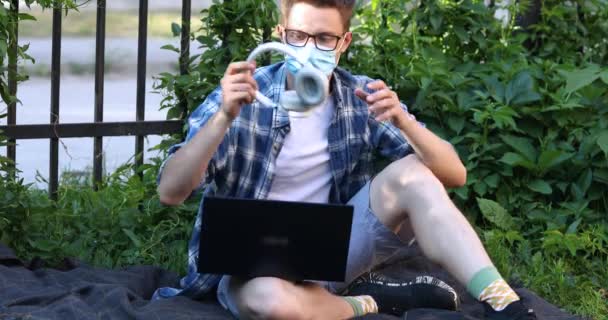 Uomo Maschera Antivirus Nel Parco Lavora Laptop Mette Cuffie — Video Stock