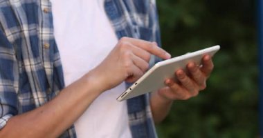 Tablet mavi tişörtlü bir adamın elinde, yakın plan.