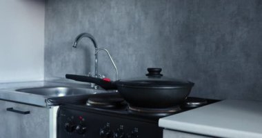 Mutfakta bir kadın kızartma tavasında yemek hazırlıyor.