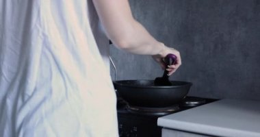 Mutfakta bir kadın kızartma tavasında yemek hazırlıyor.