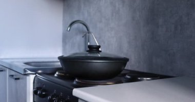 Mutfakta bir kadın kızartma tavasında yemek hazırlıyor.