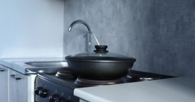 Bir kadın kızartma tavasında yemek kokluyor.