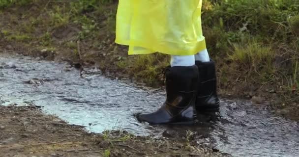 Sarı Yağmurluklu Lastik Çizmeli Bir Kadın Birikintilerinde Zıplıyor — Stok video