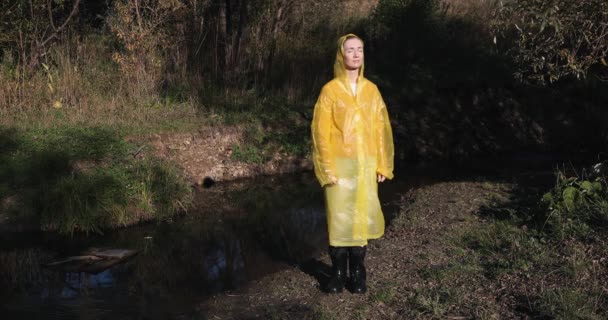 Γυναίκα Ένα Κίτρινο Αδιάβροχο Στο Δάσος Απολαμβάνοντας Τον Ήλιο — Αρχείο Βίντεο