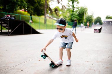 Paten parkında paten yapan bir çocuk. Gözlüklü bir çocuk paten kaymayı öğrenir..