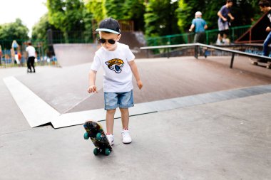 Paten parkında paten yapan bir çocuk. Gözlüklü bir çocuk paten kaymayı öğrenir..