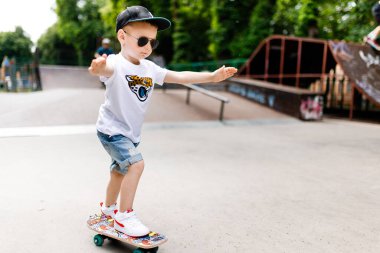 Paten parkında paten yapan bir çocuk. Gözlüklü bir çocuk paten kaymayı öğrenir..