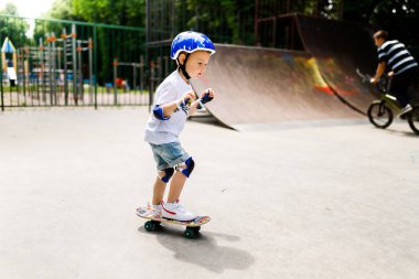 Paten parkında paten yapan bir çocuk. Çocuk tam koruma içinde paten kaymayı öğreniyor..