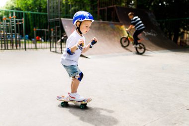 Paten parkında paten yapan bir çocuk. Çocuk tam koruma içinde paten kaymayı öğreniyor..
