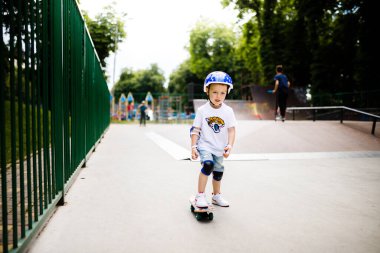 Paten parkında paten yapan bir çocuk. Çocuk tam koruma içinde paten kaymayı öğreniyor..