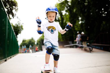 Paten parkında paten yapan bir çocuk. Çocuk tam koruma içinde paten kaymayı öğreniyor..