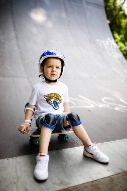 Paten parkında paten yapan bir çocuk. Çocuk tam koruma içinde paten kaymayı öğreniyor..