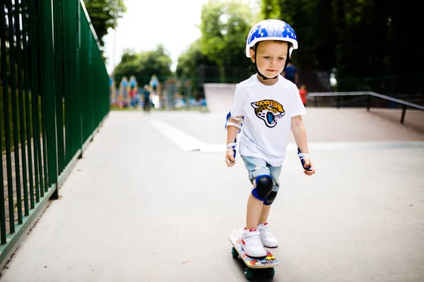 Paten parkında paten yapan bir çocuk. Çocuk tam koruma içinde paten kaymayı öğreniyor..
