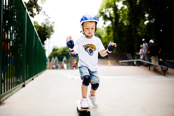 Paten parkında paten yapan bir çocuk. Çocuk tam koruma içinde paten kaymayı öğreniyor..