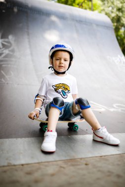 Paten parkında paten yapan bir çocuk. Çocuk tam koruma içinde paten kaymayı öğreniyor..