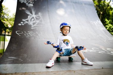 Paten parkında paten yapan bir çocuk. Çocuk tam koruma içinde paten kaymayı öğreniyor..