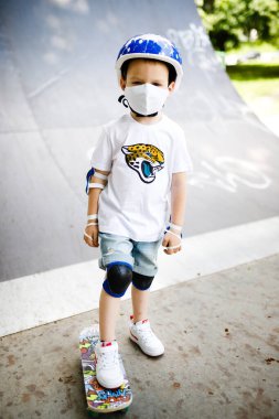 Maskeli bir çocuk karantinada paten kaymayı öğreniyor..