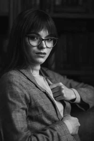 Mooi dromerig meisje met een stijlvolle scherpe bril. In de bibliotheek. — Stockfoto