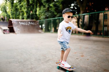 Paten parkında paten yapan bir çocuk. Gözlüklü bir çocuk paten kaymayı öğrenir..