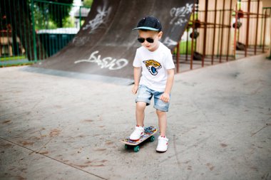 Paten parkında paten yapan bir çocuk. Gözlüklü bir çocuk paten kaymayı öğrenir..