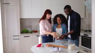 Afro-Amerikalı kız Vanessa, annesi ve babası mutfakta kek pişiriyor..