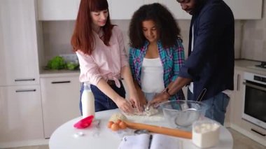Afro-Amerikalı kız Vanessa, annesi ve babası mutfakta kek pişiriyor..