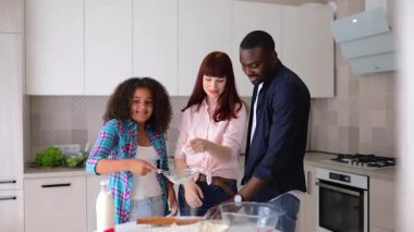 Afro-Amerikalı kız Vanessa, annesi ve babası mutfakta kek pişiriyor..