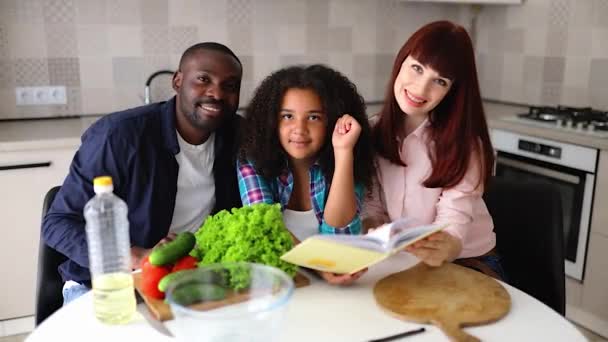 African American girl Vanessa her mom and dad in the kitchen preparing a salad. — Stock Video