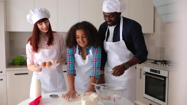Afro-Amerikaans meisje Vanessa, haar moeder en vader in de keuken, bakken van taarten. — Stockvideo