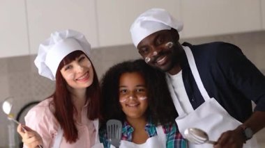 Afro-Amerikalı kız Vanessa, annesi ve babası mutfakta kek pişiriyor..