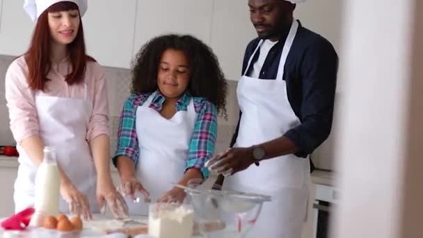 Afroamerikansk jente Vanessa, moren og faren hennes på kjøkkenet, bakekaker. – stockvideo