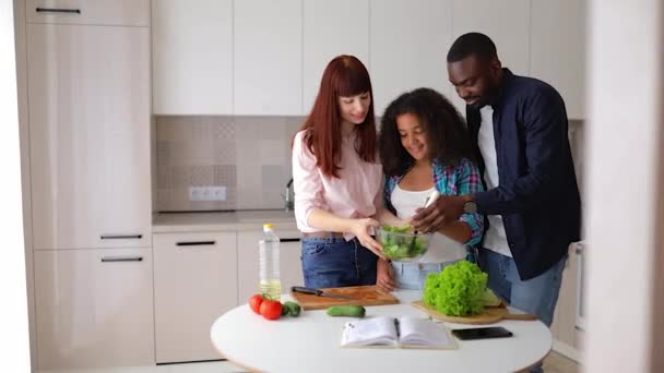 Afroamerikansk jente Vanessa, moren og faren hennes, på kjøkkenet og lagde salat. – stockvideo
