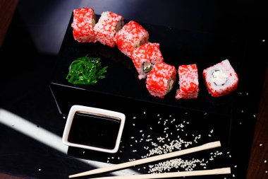 Somonlu suşi. Soya sosu, kırmızı havyar. Siyah arka planda suşi..