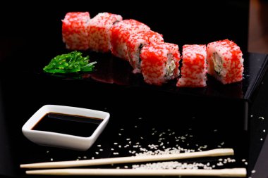 Somonlu suşi. Soya sosu, kırmızı havyar. Siyah arka planda suşi..