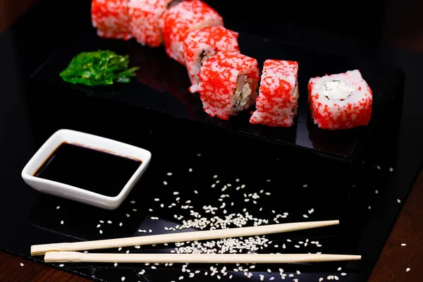Sushi with salmon. Soy sauce, red caviar. Sushi on a black background. — Stock Photo, Image