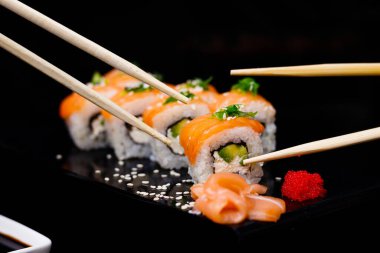 Somonlu suşi. Soya sosu, kırmızı havyar. Siyah arka planda suşi..