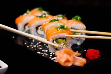 Somonlu suşi. Soya sosu, kırmızı havyar. Siyah arka planda suşi..