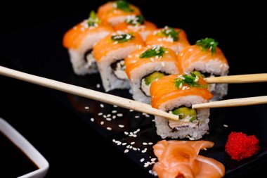 Somonlu suşi. Soya sosu, kırmızı havyar. Siyah arka planda suşi..