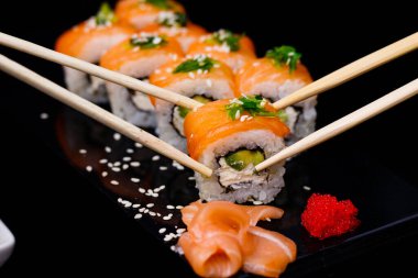 Somonlu suşi. Soya sosu, kırmızı havyar. Siyah arka planda suşi..