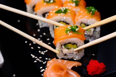 Somonlu suşi. Soya sosu, kırmızı havyar. Siyah arka planda suşi..