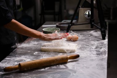 Şef profesyonel bir mutfakta hamur işleri hazırlıyor. Koyu arkaplan.