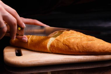 Ev yapımı beyaz ekmek büyük bir bıçakla kesilir. Evde pişirme.