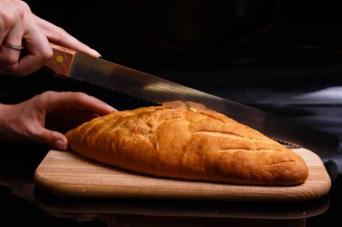 Ev yapımı beyaz ekmek büyük bir bıçakla kesilir. Evde pişirme.