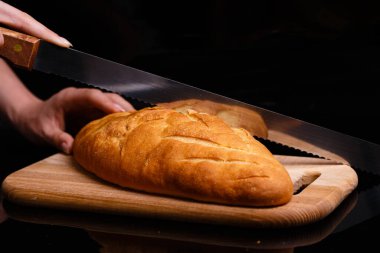 Ev yapımı beyaz ekmek büyük bir bıçakla kesilir. Evde pişirme.